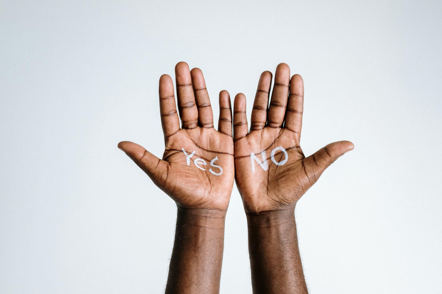 image of two hands held palm up. One has 'yes' written on it, the other has no'